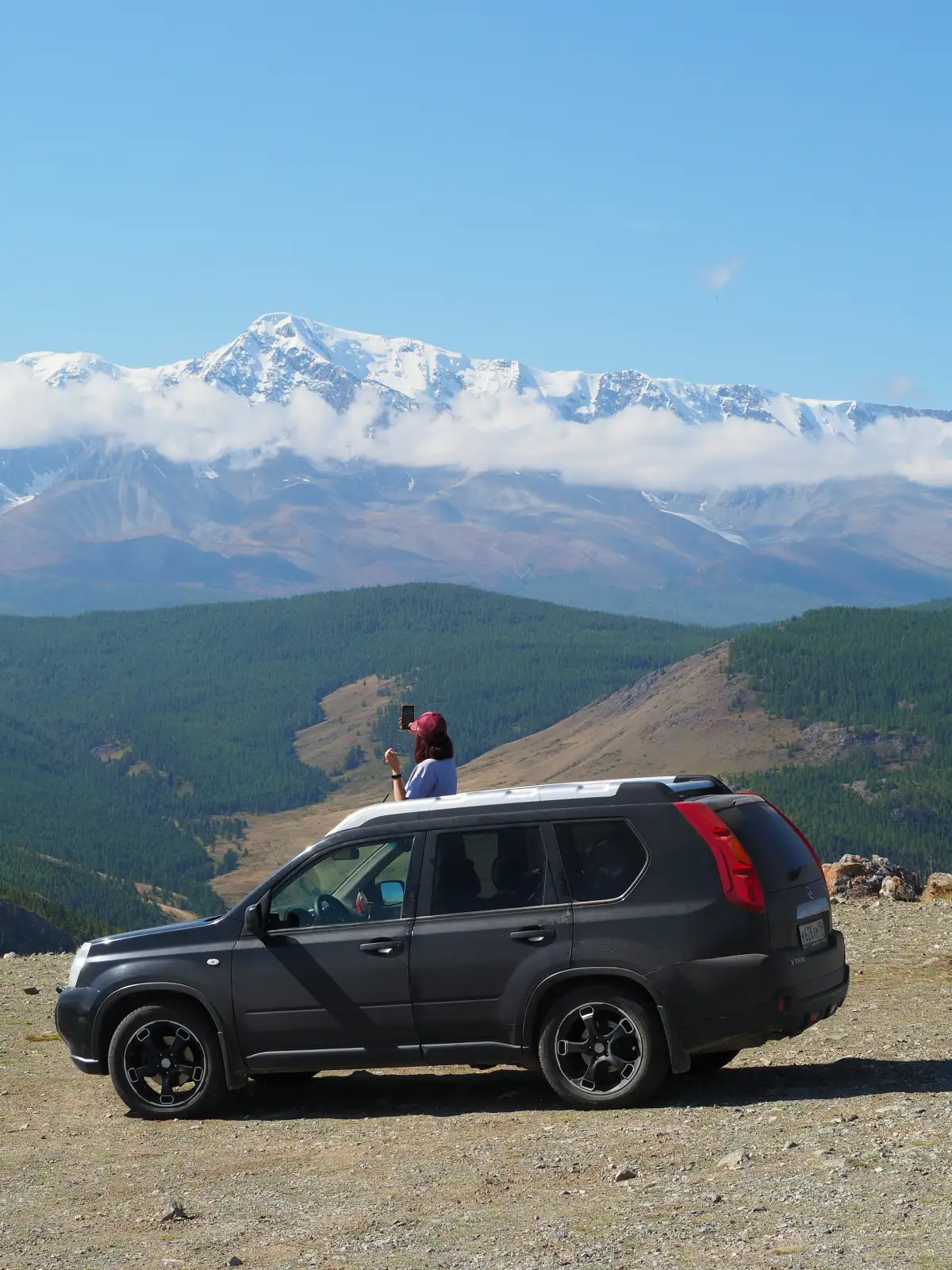 A person standing on top of a car in the mountains